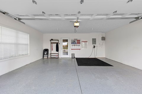 A spacious garage with a black mat on the floor and a red sign on the door.