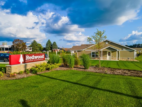 A sign for Redwood Apartment Homes is in front of a building.
