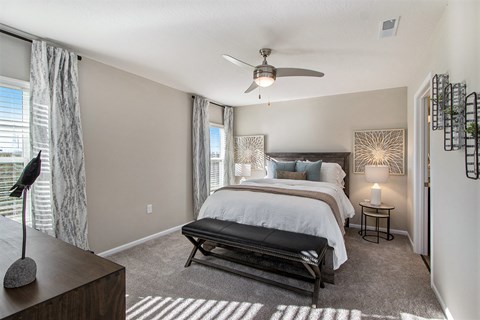 A bedroom with a large bed and a ceiling fan.