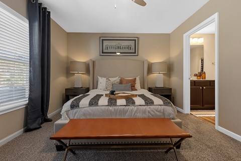 A bedroom with a bed, two lamps, and a picture on the wall.
