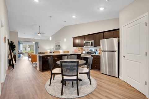 A modern kitchen with a dining table and chairs in the middle.