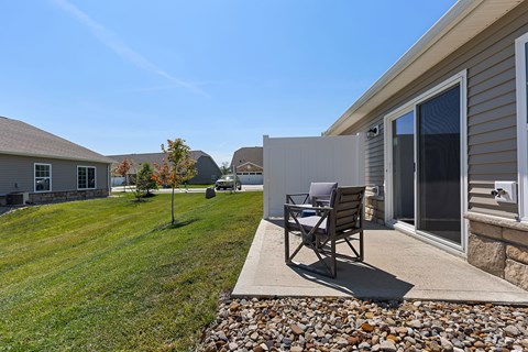 A patio with a chair and table is in front of a house.