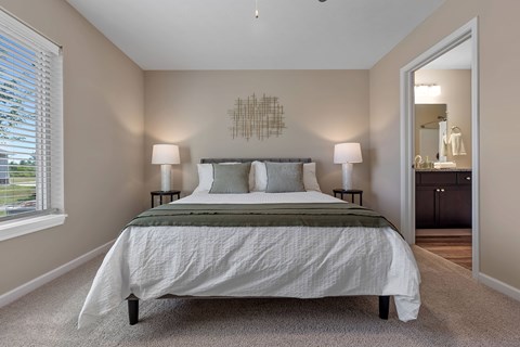 A bedroom with a large bed and two lamps.