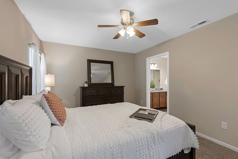 A bedroom with a bed, dresser, mirror, and a ceiling fan.