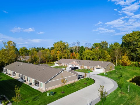 A large building with a grey roof is surrounded by green grass and trees.