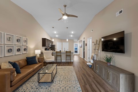 A living room with a brown couch and a ceiling fan.
