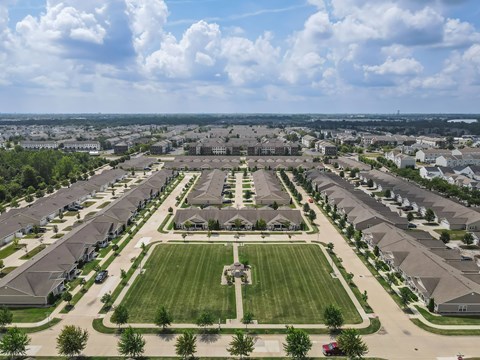 A large suburban housing development with a central green space and a road running through it.