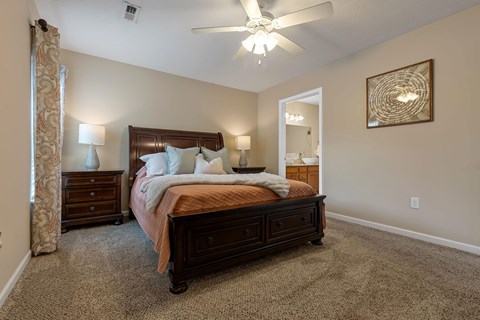 A bedroom with a large bed, a dresser, and a ceiling fan.