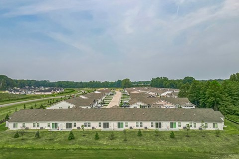 A large white building with green trim is surrounded by a grassy field.