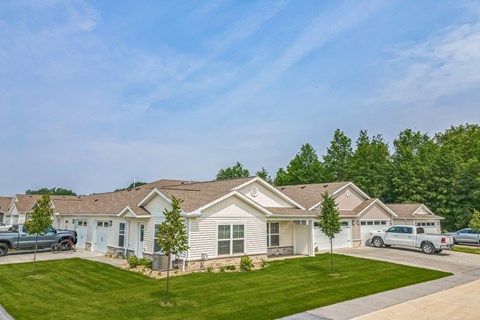 A house with a green lawn and a blue sky in the background.