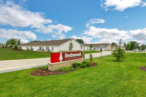 A sign for Redwood Assisted Living is in front of a building.