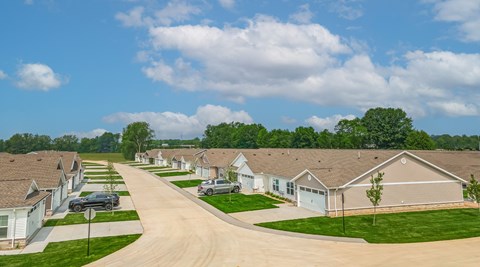 A residential street with houses on both sides and cars parked in front.