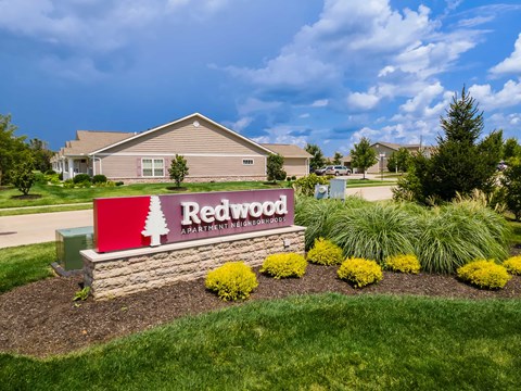A sign for Redwood Apartment Homes is in front of a building.