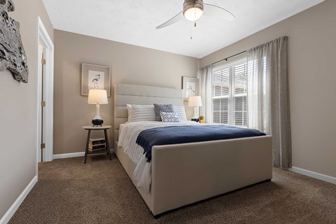 A bedroom with a large bed and a ceiling fan.