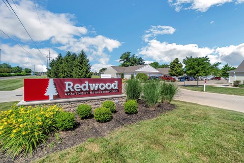 A sign for Redwood Apartment Homes is in front of a building.