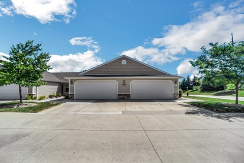 A two-car garage with a brown roof is situated in front of a house.