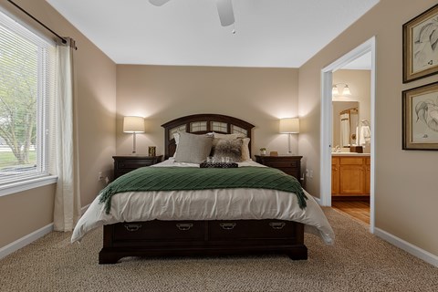 A bedroom with a large bed and a carpeted floor.
