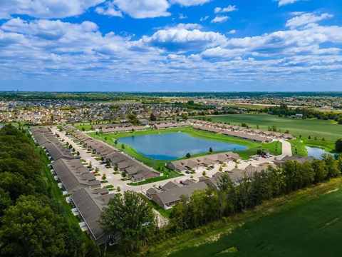 A bird's eye view of a residential area with a large swimming pool and a green field.