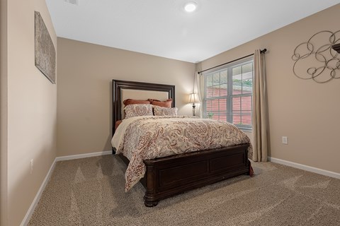 A bedroom with a large bed and a window with curtains.