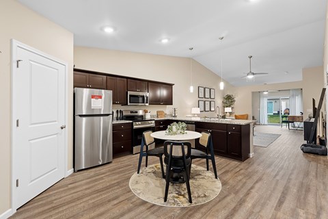 A kitchen with a dining table and chairs in the middle of the room.