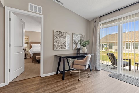 A room with a desk and chairs with a view of a building outside.