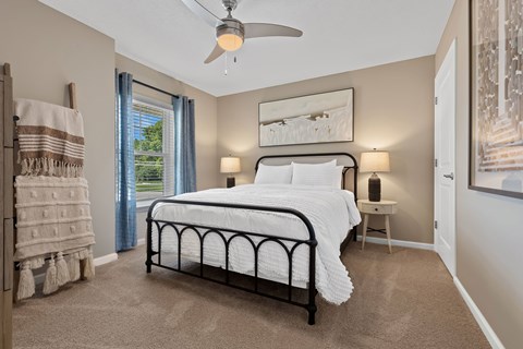A bedroom with a large bed and a ceiling fan.