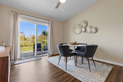 A dining room with a table set for two and a view of the outdoors.