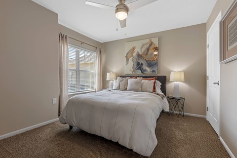 A bedroom with a large bed and a ceiling fan.