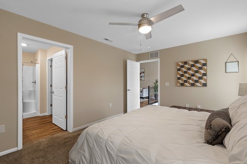 A bedroom with a bed, a ceiling fan, and a checkerboard patterned picture on the wall.