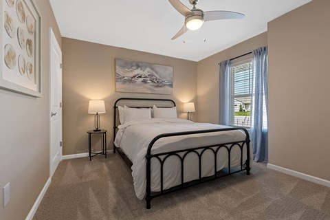 A bedroom with a large bed and a ceiling fan.