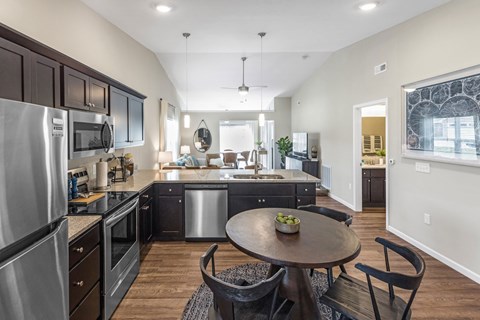 A modern kitchen with dark wood cabinets and stainless steel appliances.