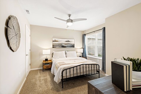 A bedroom with a bed, nightstands, and a ceiling fan.