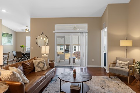 A living room with a brown leather couch and a round table in the center.