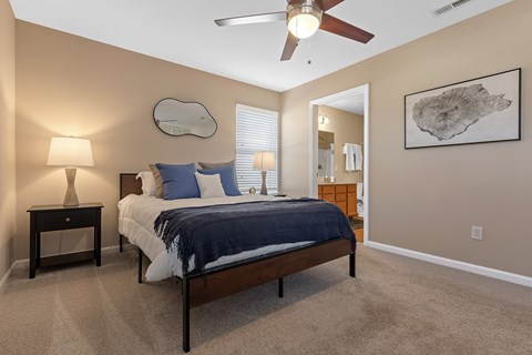 A bedroom with a bed, nightstand, and a ceiling fan.