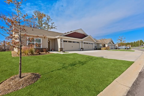 A house with a brown roof and a tree in front of it.