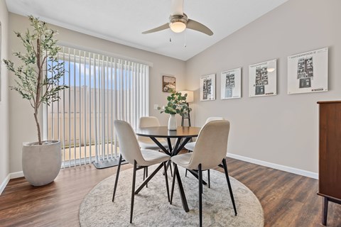 A dining room with a table, chairs, and a plant.