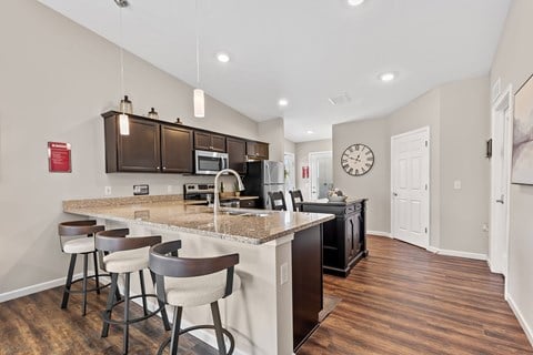 A kitchen with a bar area and a clock on the wall.