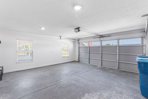A spacious garage with a concrete floor and a grey garage door.