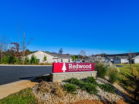 A sign for Redwood Apartment Neighborhood in front of some houses.