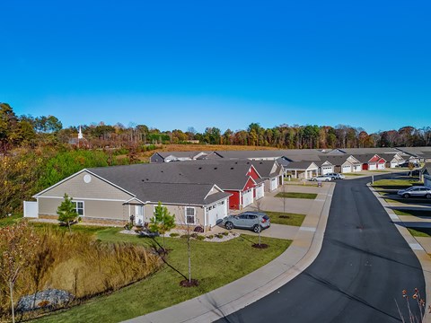 A residential street with houses on both sides and cars parked in front.