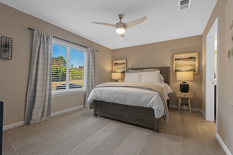 A bedroom with a large bed and a ceiling fan.