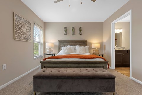 A bedroom with a large bed and a bench in front of it.