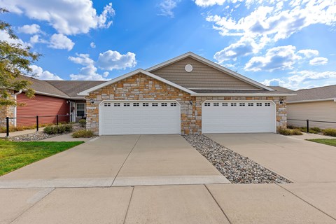 A house with a red garage door and a stone border on the driveway.