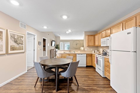 A kitchen with a table and chairs in the foreground and a refrigerator on the right.