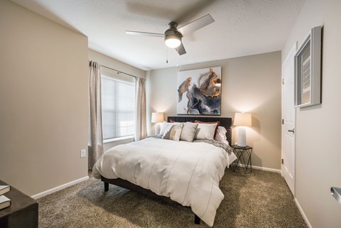 A bedroom with a large bed and a ceiling fan.