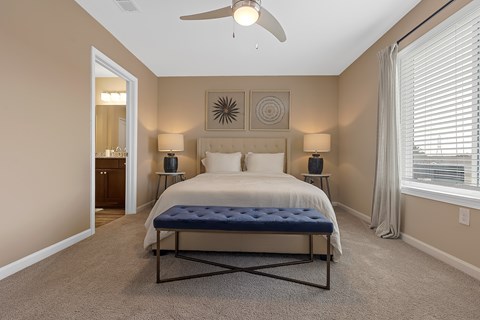 A bedroom with a bed, two lamps, and a ceiling fan.