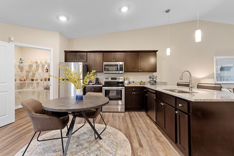 A kitchen with brown cabinets and a round table with chairs.