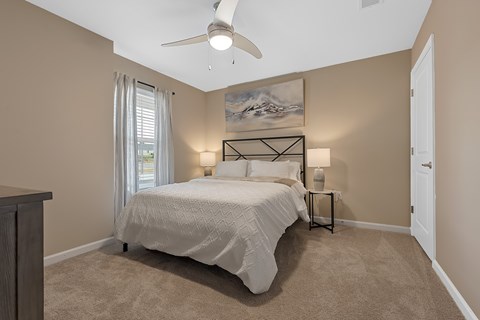 A bedroom with a large bed and a ceiling fan.