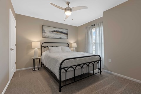 A bedroom with a bed, nightstand, and a ceiling fan.