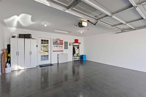 A spacious room with a grey floor and white walls, equipped with a ceiling lighting system and a few cabinets.
